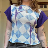 Person wearing a blue and purple patterned shirt with short sleeves.